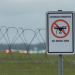 No drone zone sign behind a fence at dusk