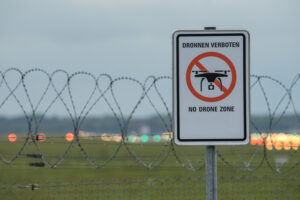 No drone zone sign behind a fence at dusk